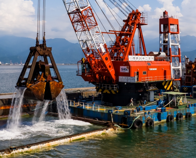 港湾で作業する大型の赤い浚渫クレーン船
