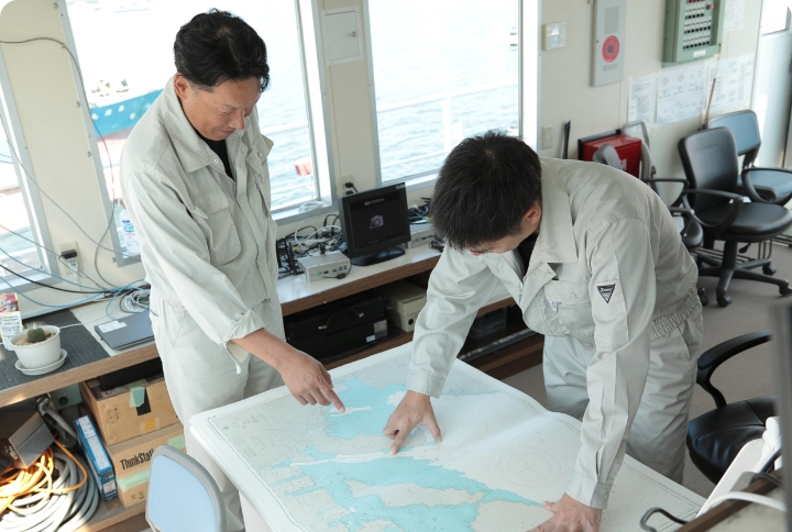 白い制服を着た二人の男性が地図を見ながら話し合っている様