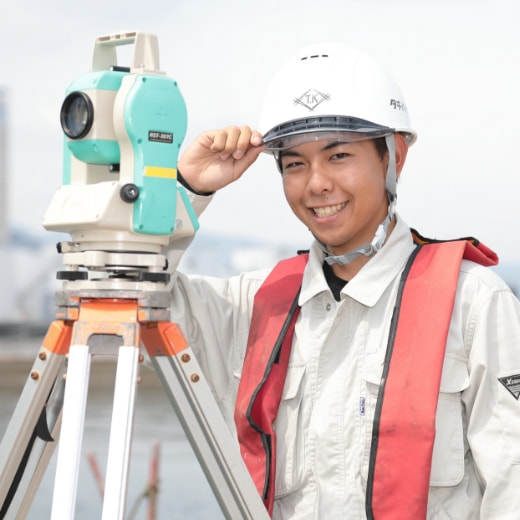 測量機器を使う建設作業員の笑顔の写真