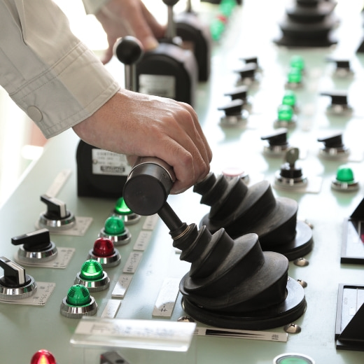 工場の制御パネルでジョイスティックを操作する作業員の手