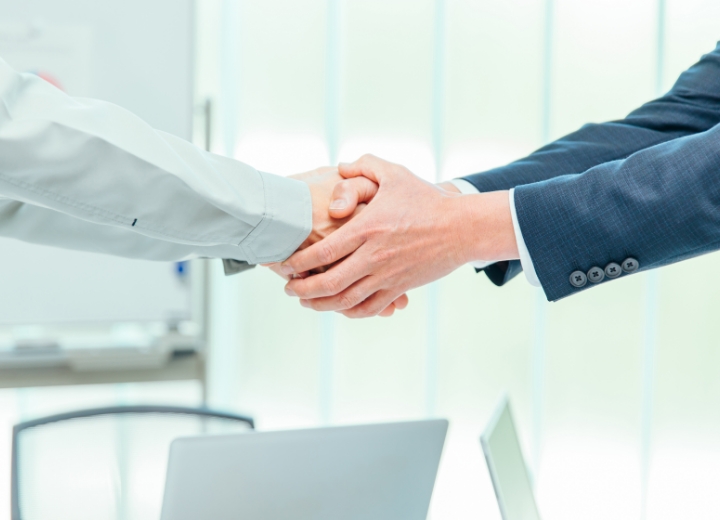 ビジネスマン同士の握手、オフィスの会議室での契約や協力のイメージ。