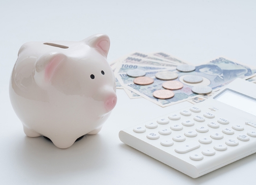 貯金箱と電卓、日本円の紙幣と小銭。