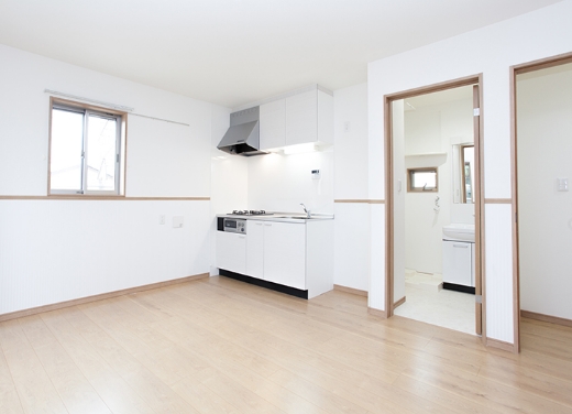 明るいリビングとシンプルなキッチン付きの新築住宅の内装写真