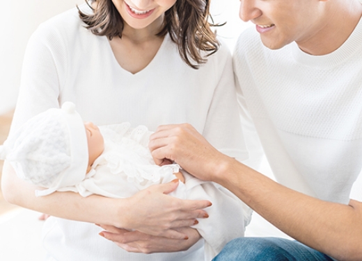 新生児を抱く幸せな若い日本人夫婦の写真