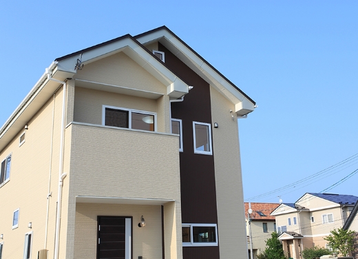 新築モダン住宅の外観、青空の下で明るいベージュと茶色のツートンカラーの家