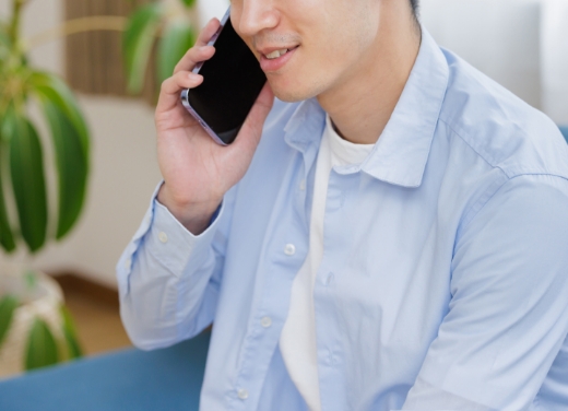 スマートフォンで通話する若い男性、カジュアルな服装、室内。