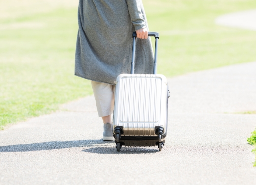 手押しトランクを引く旅行者の後ろ姿。