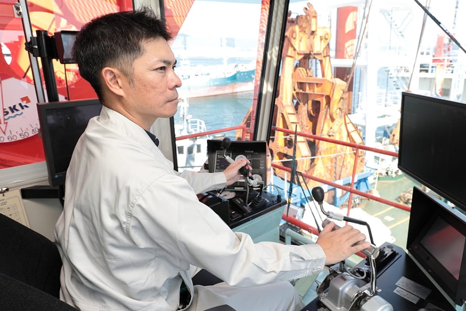 クレーンオペレーターが港でクレーンを操作している様子。