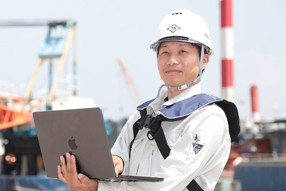 建設現場でノートパソコンを使うヘルメット姿の作業員