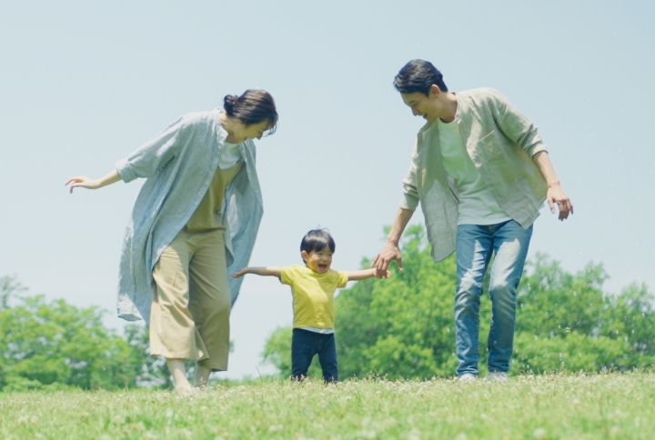 公園で子供と遊ぶ笑顔の家族の写真