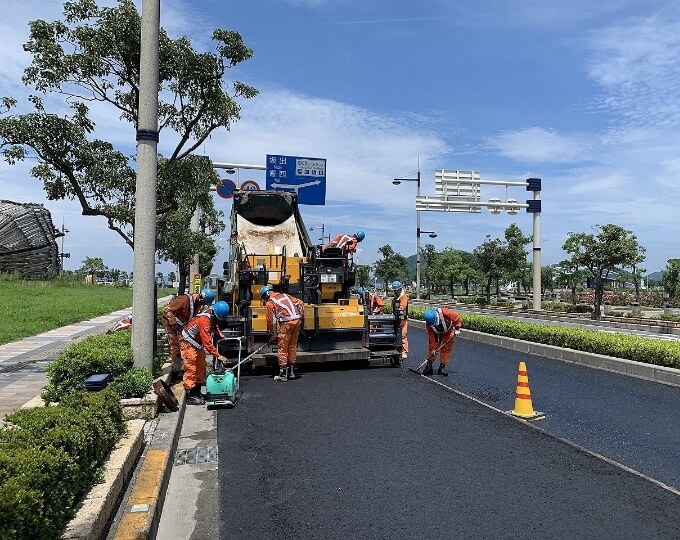 工業地域で作業している労働者たちが道路工事を行っている様子です。