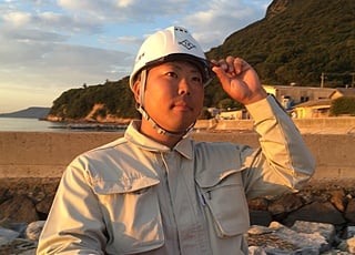 岩だらけのビーチに立つヘルメットをかぶった男性の画像です。